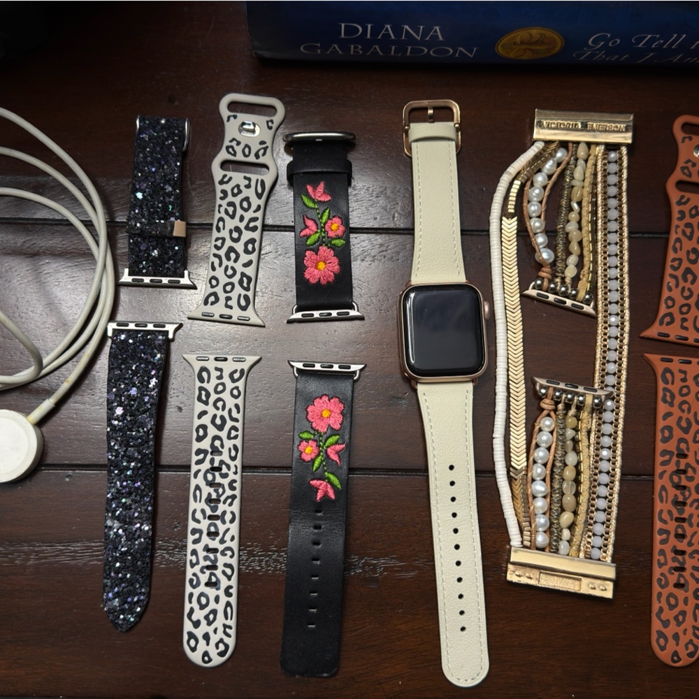 Apple Watch with Beige Band and Assorted Black, White, Gold, and Brown Straps